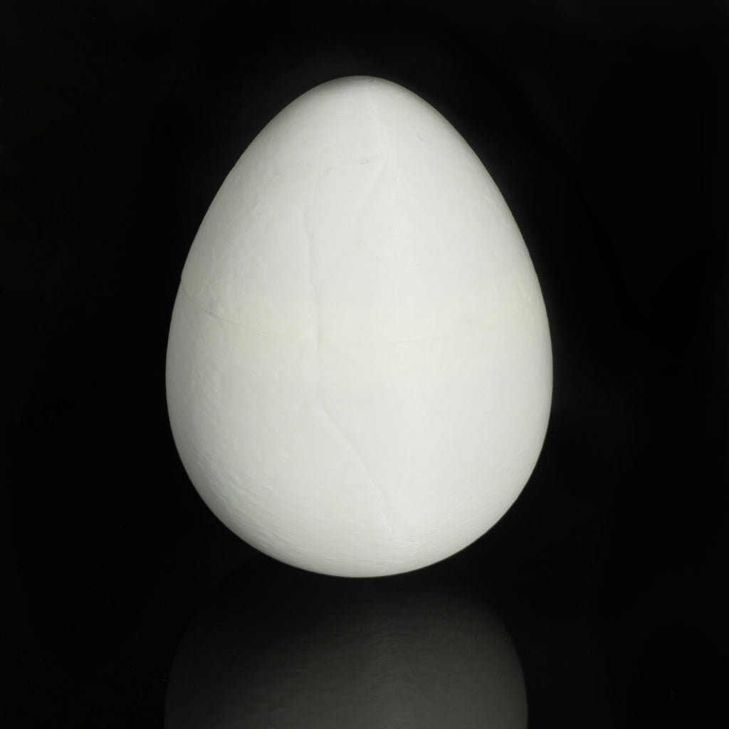 White 3D-printed dino egg standing closed on a black background