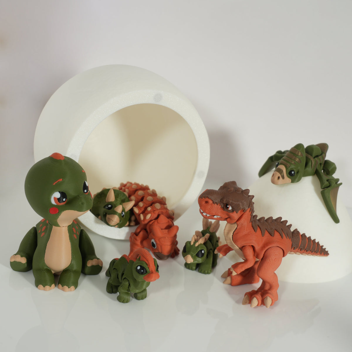 Assorted 3D-printed dinosaur figures in front of the open dino egg