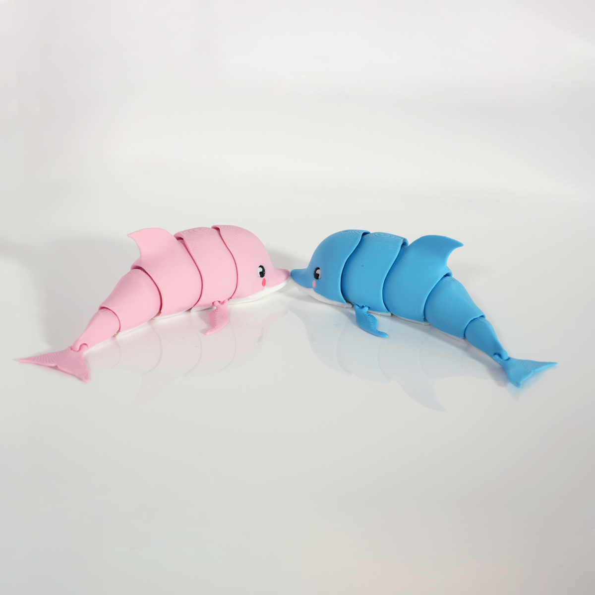 Pink and blue articulated dolphins lying side by side