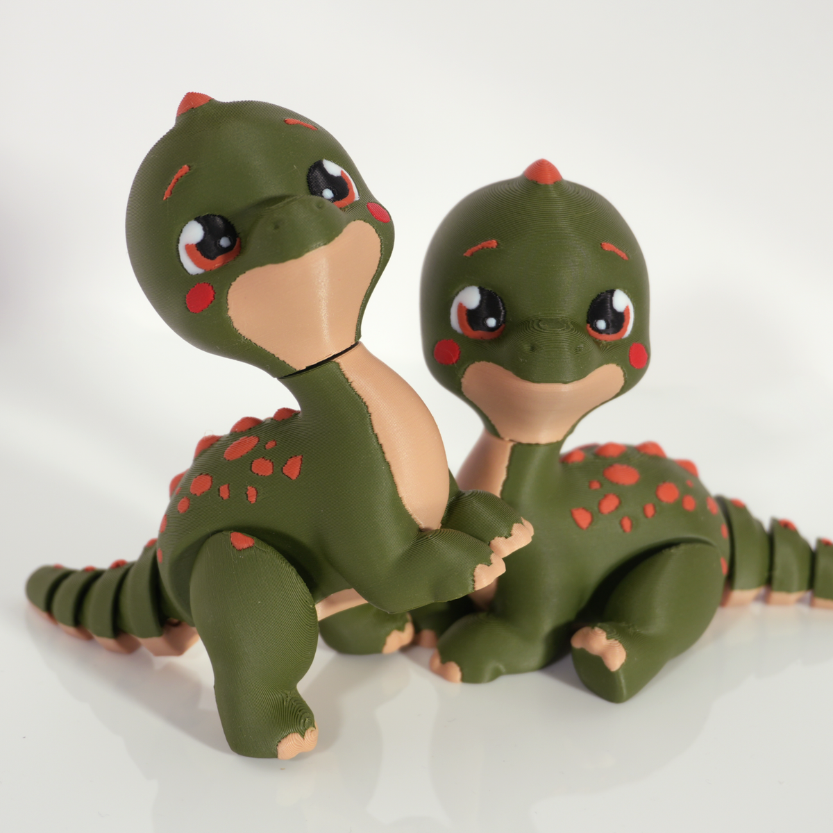 Close-up of two Tiny Diny Brachiosaurus prints with big eyes and rosy cheeks