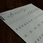 Printed calligraphy worksheet with pointed-pen practice strokes on guidelines