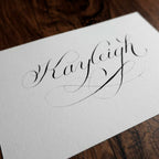 Angled close-up of "Kayleigh" in copperplate calligraphy showing the paper texture