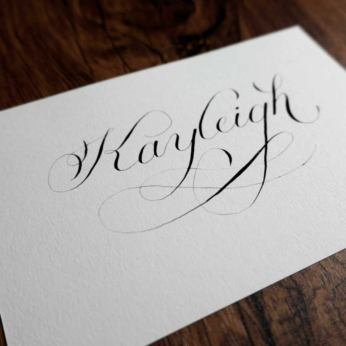 Angled close-up of "Kayleigh" in copperplate calligraphy showing the paper texture