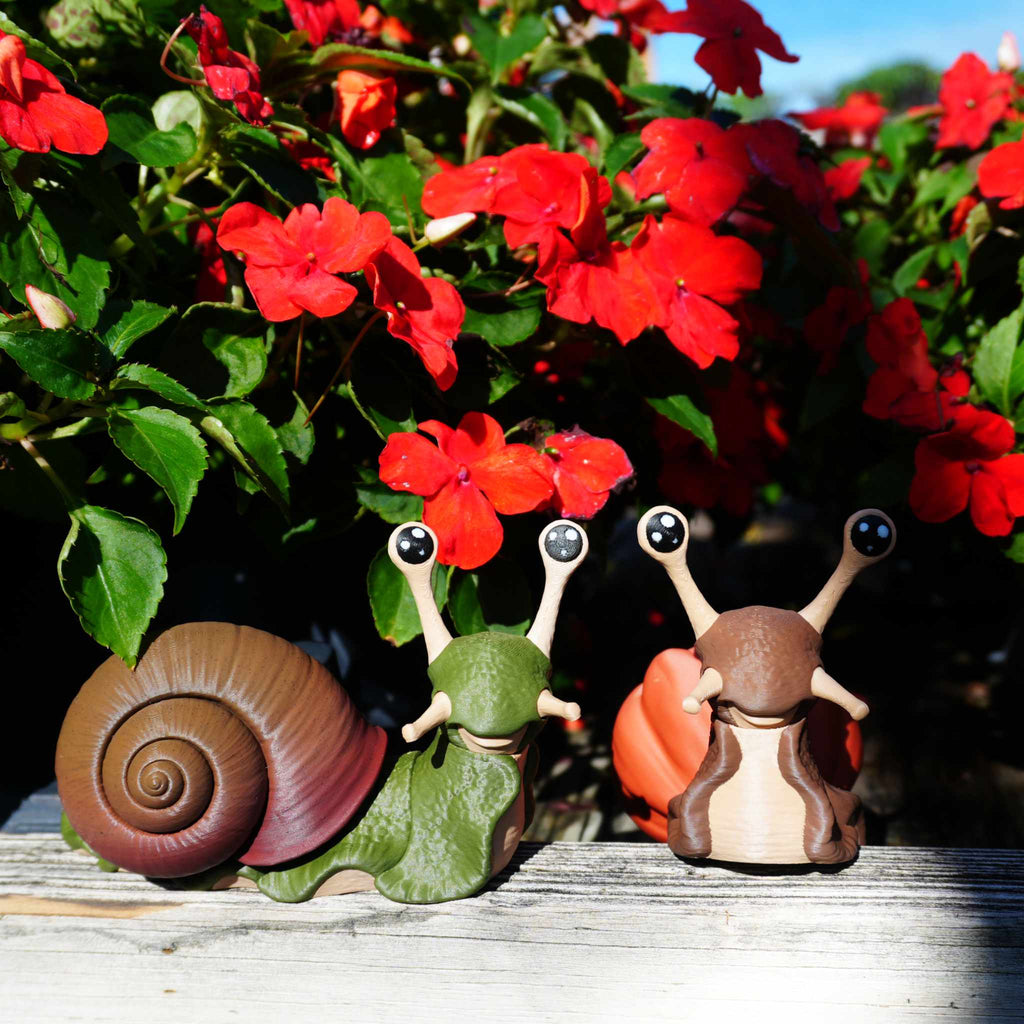 Articulated snails in front of red impatiens flowers